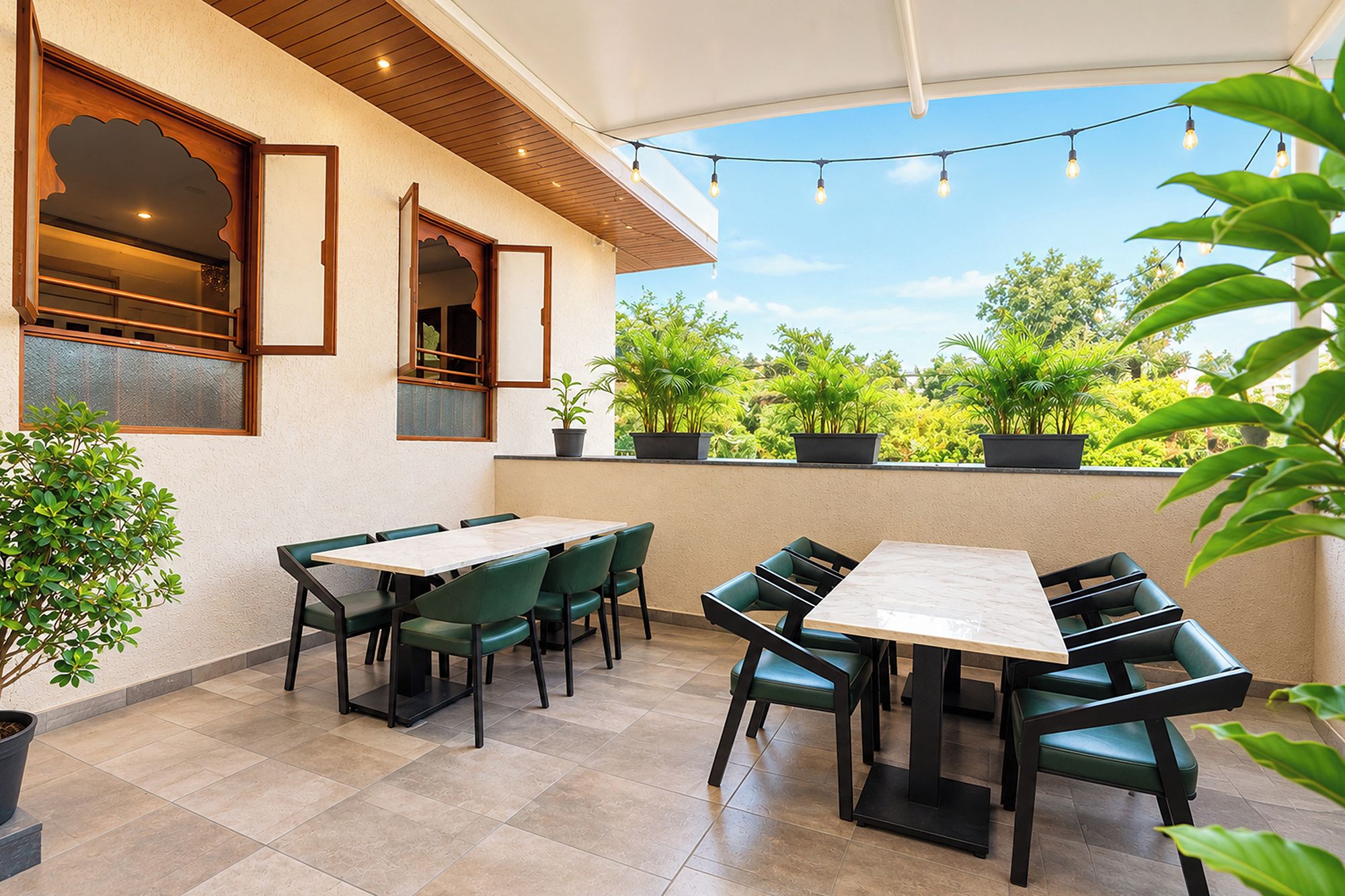 An outdoor patio with a table and chairs, potted plants, and string lights.