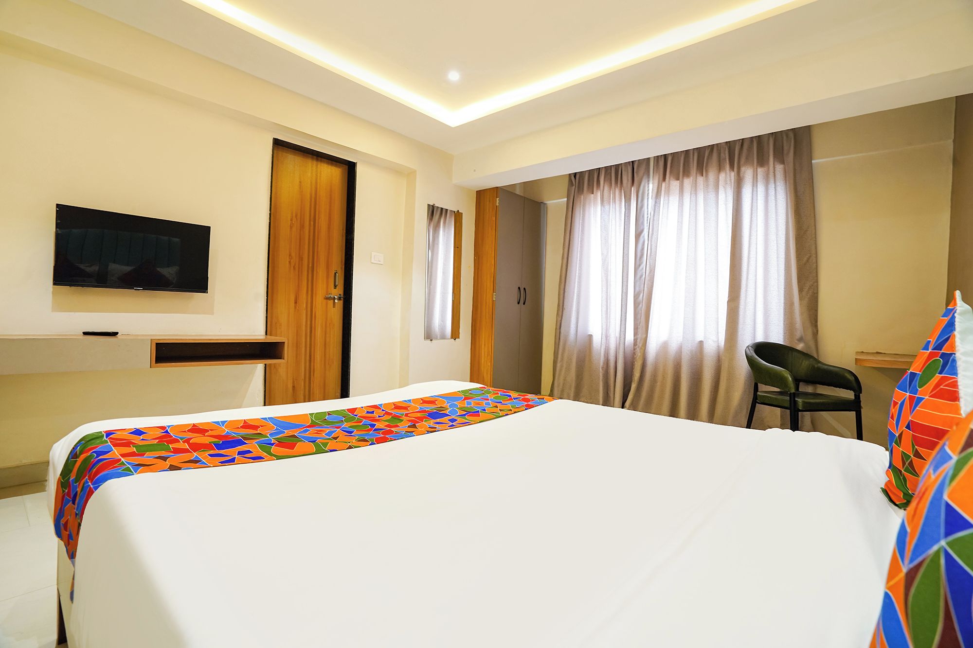 A hotel room with a bed, a television, a desk, and a chair.
