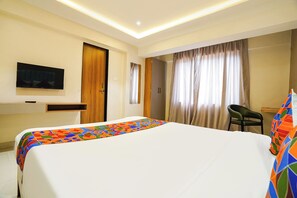 Habitación de hotel con una cama, televisión, escritorio y silla.