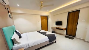 Habitación de hotel con cama, ventilador de techo, televisión y puerta.