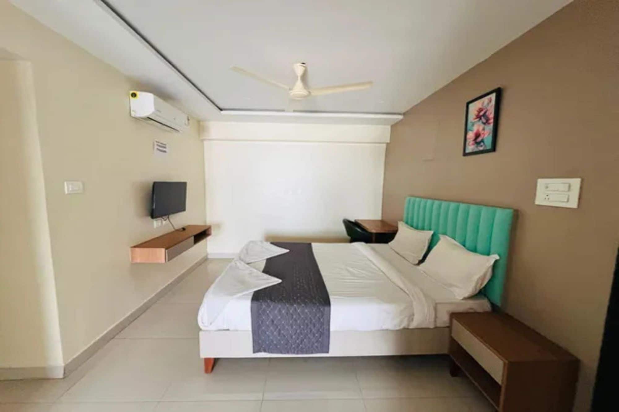 A hotel room with a bed, a television, a ceiling fan, and a window.