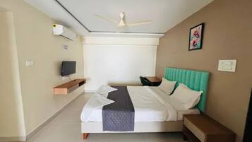 A hotel room with a bed, a television, a ceiling fan, and a window.