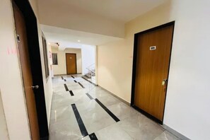 A hotel corridor with a wooden door marked '101' and a tiled floor with black stripes.