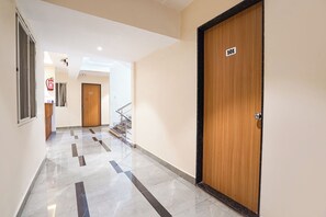 Pasillo de hotel con una puerta de madera con el número '101' y un extintor en la pared.