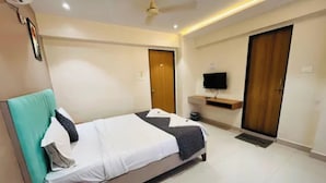 Habitación de hotel con cama, escritorio, televisor y armario.
