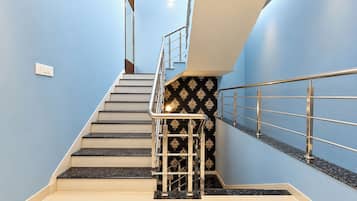 A staircase with a metal handrail and a patterned wall.