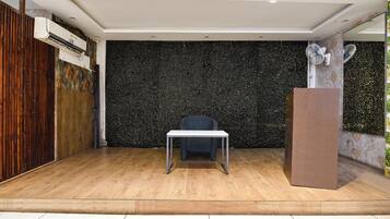 Una habitación con piso de madera, una mesa blanca, una pared con motas negras y una puerta de madera.