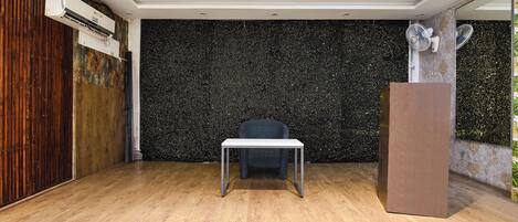 Une pièce avec un plancher en bois, une table blanche, un mur noir à motifs et une porte en bois.