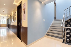 Un pasillo de hotel con una escalera, puertas y un cartel en la pared.