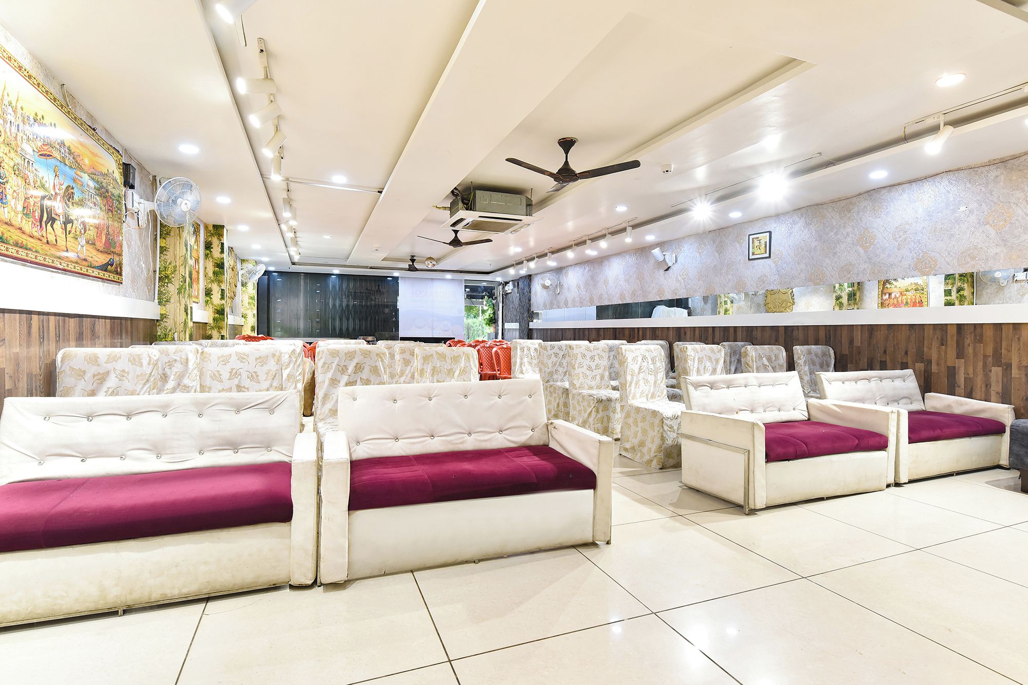 A restaurant with booth seating, ceiling fans, and a decorative mural on the wall.