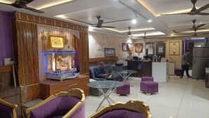 A hotel lobby with a reception desk, seating area, decorative wall, ceiling fans, and a refrigerator. - Fabhotel Rudraksh Inn (Indore)