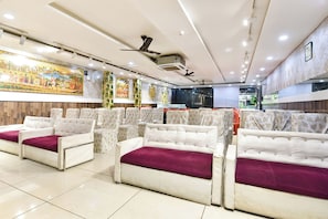 Un restaurante con filas de asientos acolchados, ventiladores de techo y decoración mural.