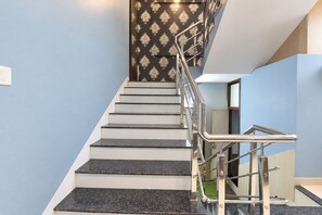 A staircase with a metal handrail, white steps, and a patterned wall. - Fabhotel Rudraksh Inn (Indore)