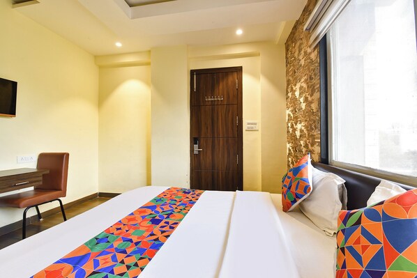 Una habitación de hotel con cama, una silla, una puerta y una ventana.
