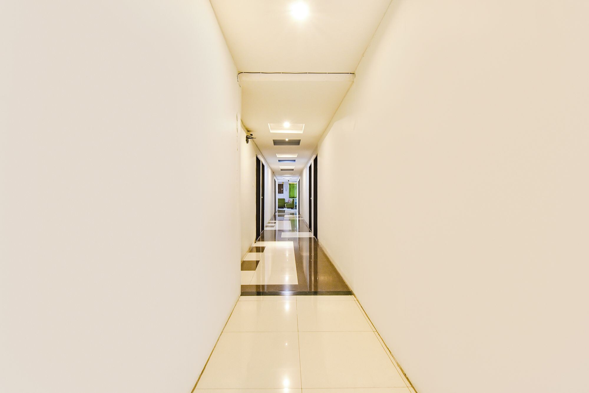 Un pasillo largo y estrecho con piso reflectante y paredes blancas.
