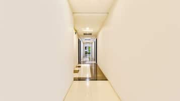 Un pasillo largo y estrecho con piso reflectante y paredes blancas.