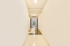 Un pasillo largo y estrecho con piso reflectante y paredes blancas.