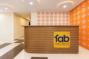 Una mesa de recepción con el logotipo de 'fab hotels' y una pared con diseño a la derecha.