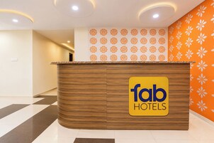 Una mesa de recepción con el logotipo de 'fab hotels' y una pared con diseño a la derecha.
