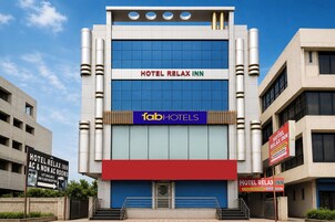 Un edificio de hotel con un cartel de Hotel Relax Inn, que indica habitaciones con aire acondicionado y sin aire acondicionado, y una recepción en el segundo piso.