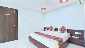 A bedroom with a bed, bedside table, nightstand, ceiling fan, and a door.