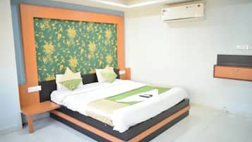 A bedroom with a bed, a nightstand, a wall-mounted air conditioner, and a built-in shelf.