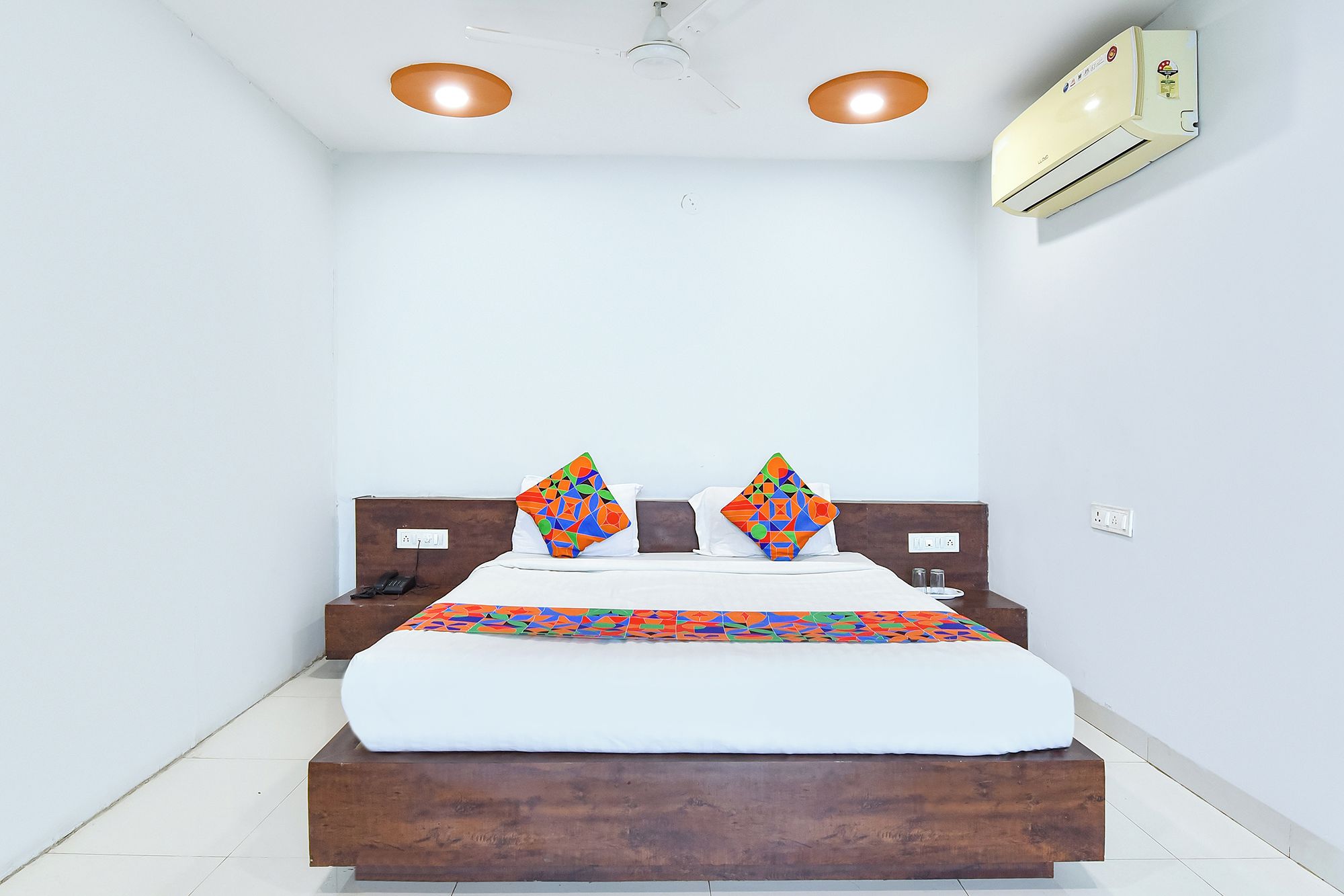 A bedroom with a bed, two pillows, a ceiling fan, and an air conditioning unit.