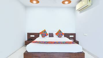 A bedroom with a bed, two pillows, a ceiling fan, and an air conditioning unit.
