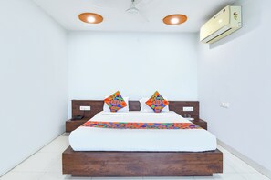 A bedroom with a bed, two pillows, a ceiling fan, and an air conditioning unit. - FabHotel Relax Inn (Dewas)