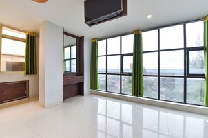Una habitación de hotel con un ventanal grande, un televisor de pantalla plana y un armario de madera.
