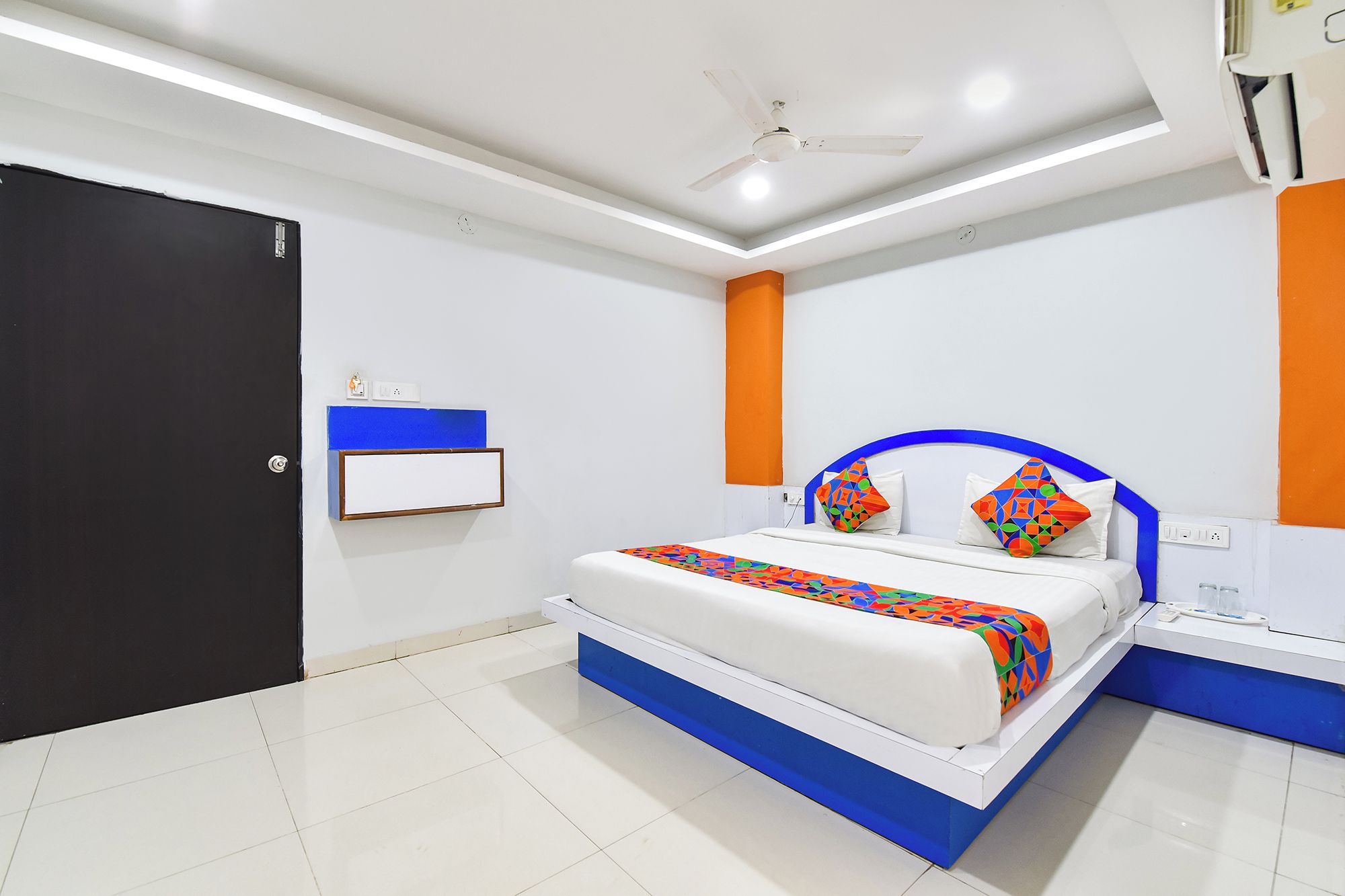Un dormitorio moderno con cama, mesitas de noche, ventilador de techo y una puerta.