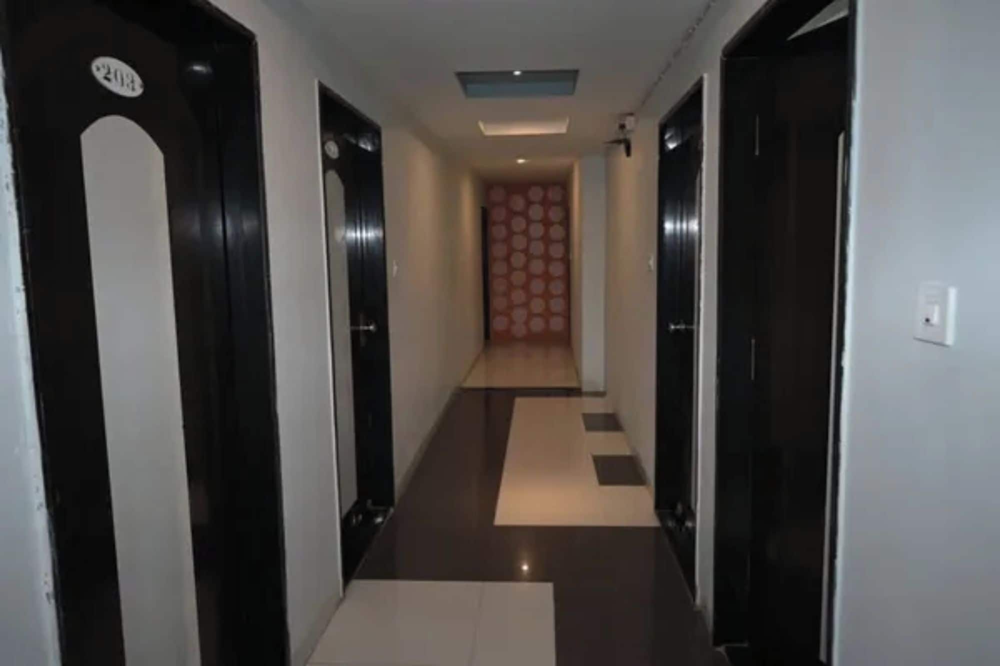A hallway with doors on both sides, a patterned wall at the end, and a ceiling light.
