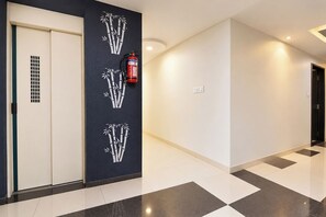 A hallway with a fire extinguisher mounted on the wall, a door with a vent, and a patterned floor.
