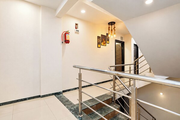 A modern interior with a staircase, metal handrails, a fire extinguisher, and recessed lighting.