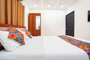 A hotel room with a large bed, wooden headboard, and a wardrobe. - FabHotel Jaihind Building (Pune)
