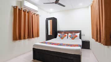 Un dormitorio con cama, ventilador de techo, equipo de aire acondicionado y cortinas.