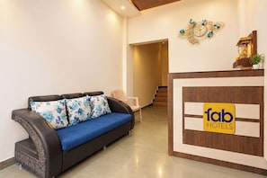 A hotel reception area with a sofa, a staircase, and a decorative wall piece.