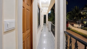 A corridor with a wooden door, a light switch, and a balcony with a railing. - Fabhotel Avshree Crown Beach Stay (Calangute)