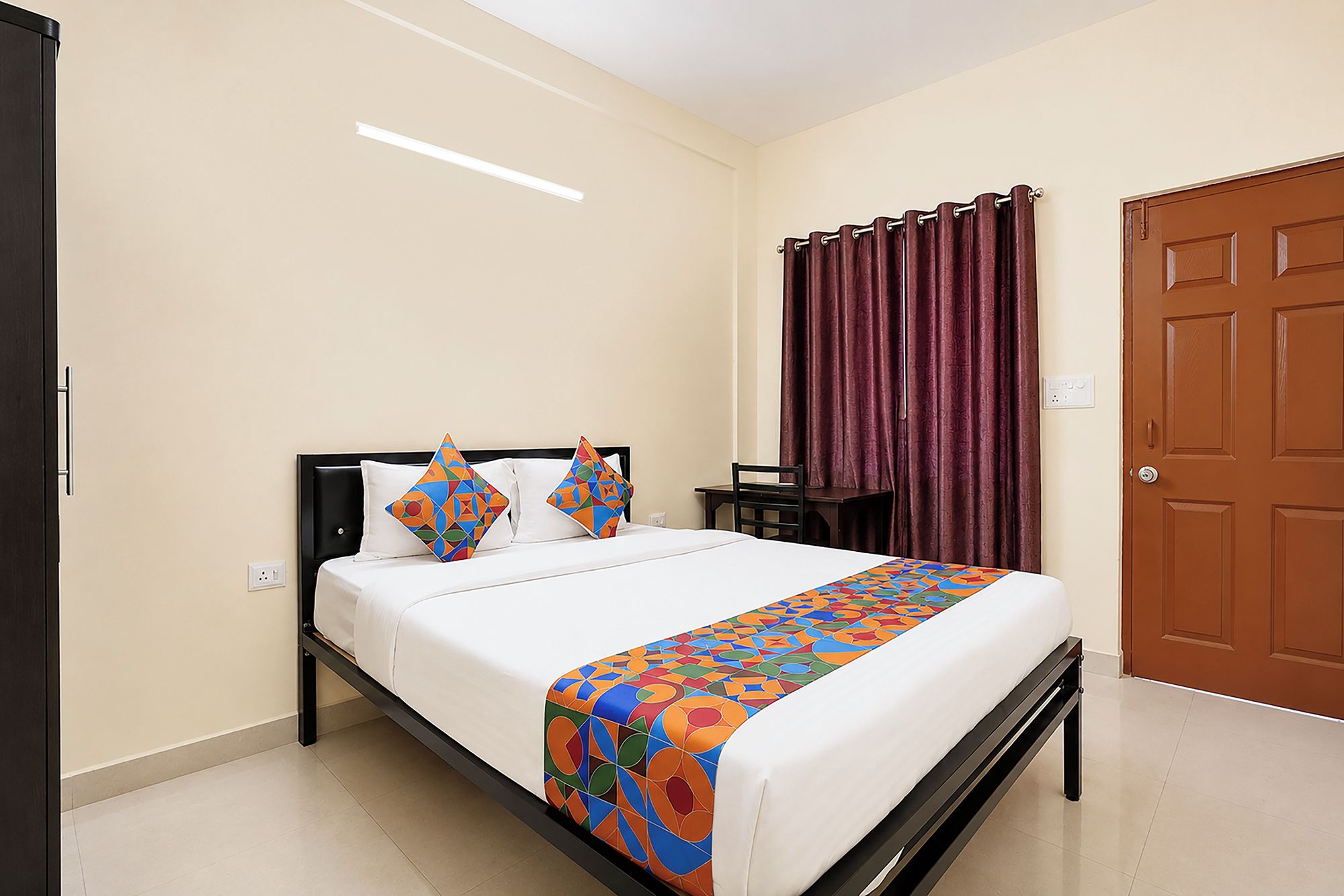 A hotel room with a bed, a desk, and a door.