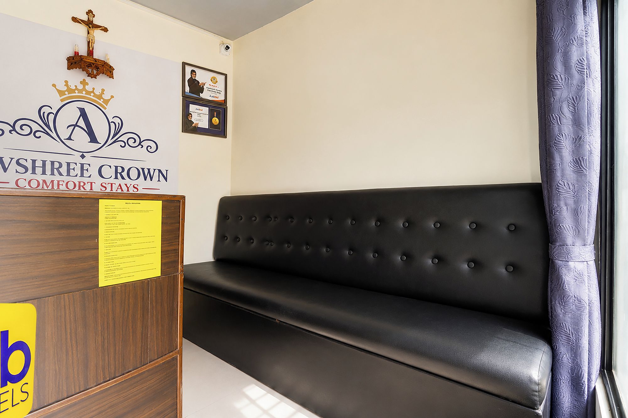Een receptiegedeelte met een zwarte lederen bank, een houten receptiebalie en een aan de muur bevestigd kruis.