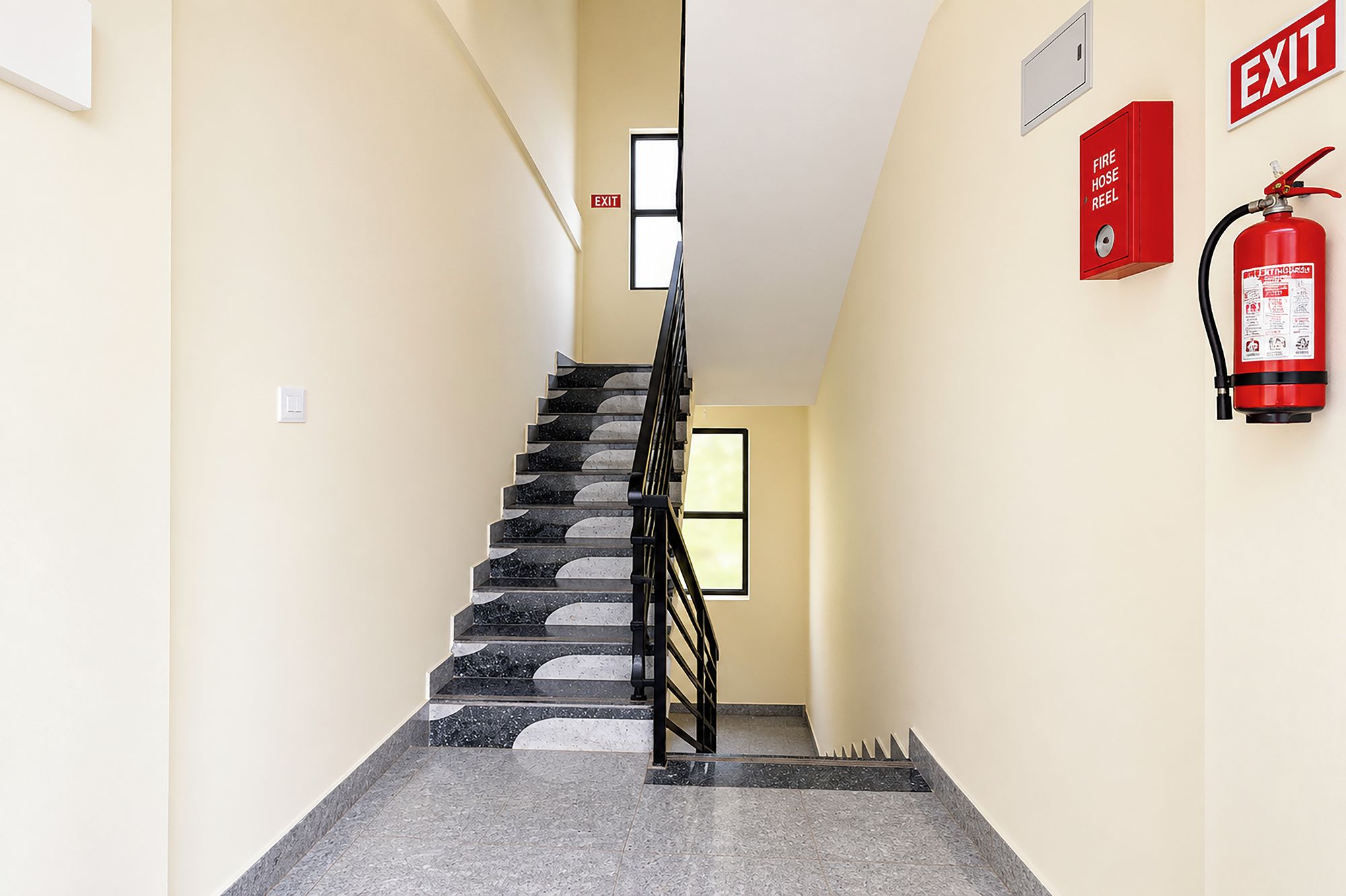 Una escalera con un carrete de manguera contra incendios y un letrero de salida.