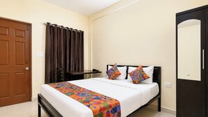 A hotel room with a bed, a nightstand, a chair, a door, and a mirror. - Fabhotel Avshree Crown Beach Stay (Calangute)