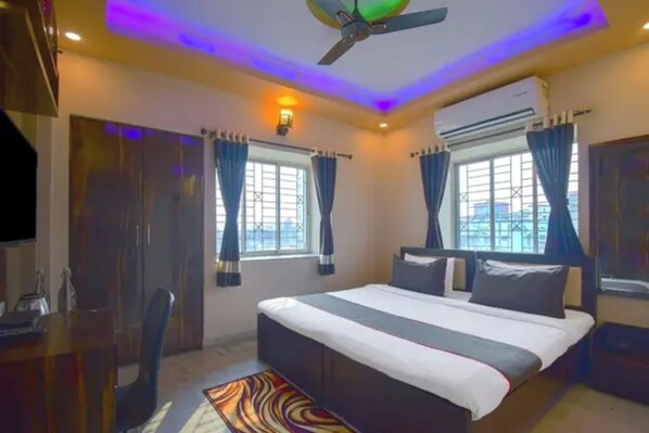 Una habitación de hotel con una cama, un escritorio, una silla y un ventilador de techo.