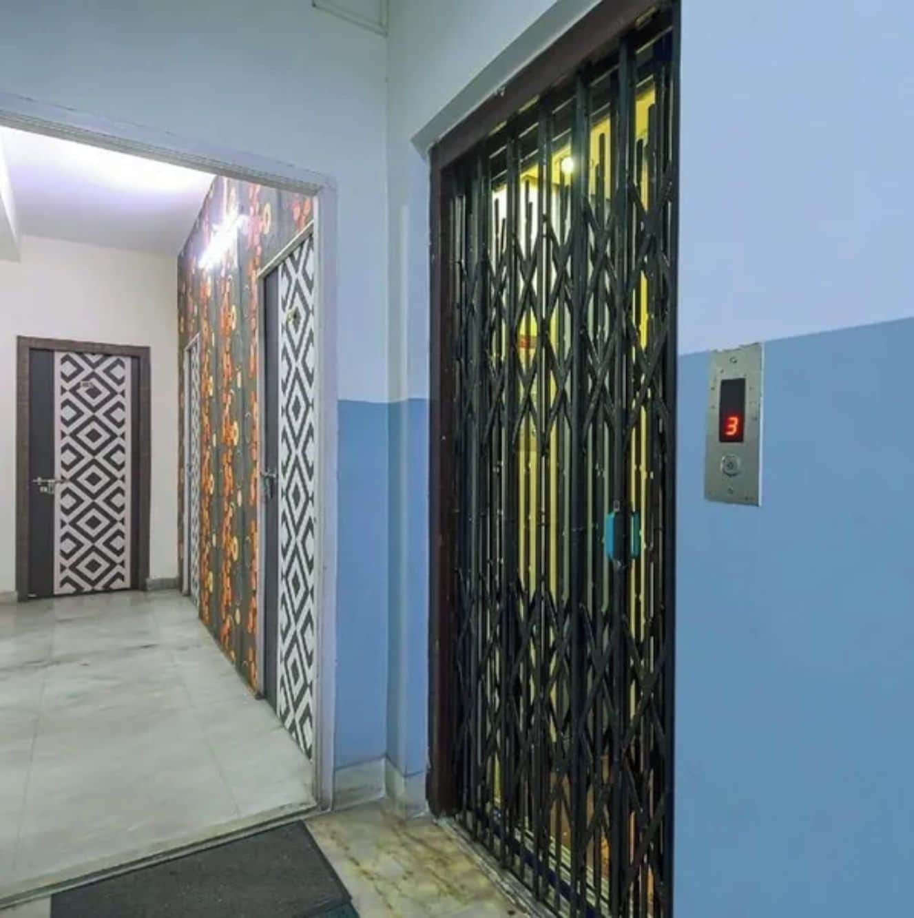 Un pasillo con puertas decoradas y un portón de metal que conduce a un ascensor.
