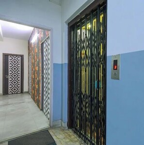 Un pasillo con puertas decoradas y un portón de metal que conduce a un ascensor.
