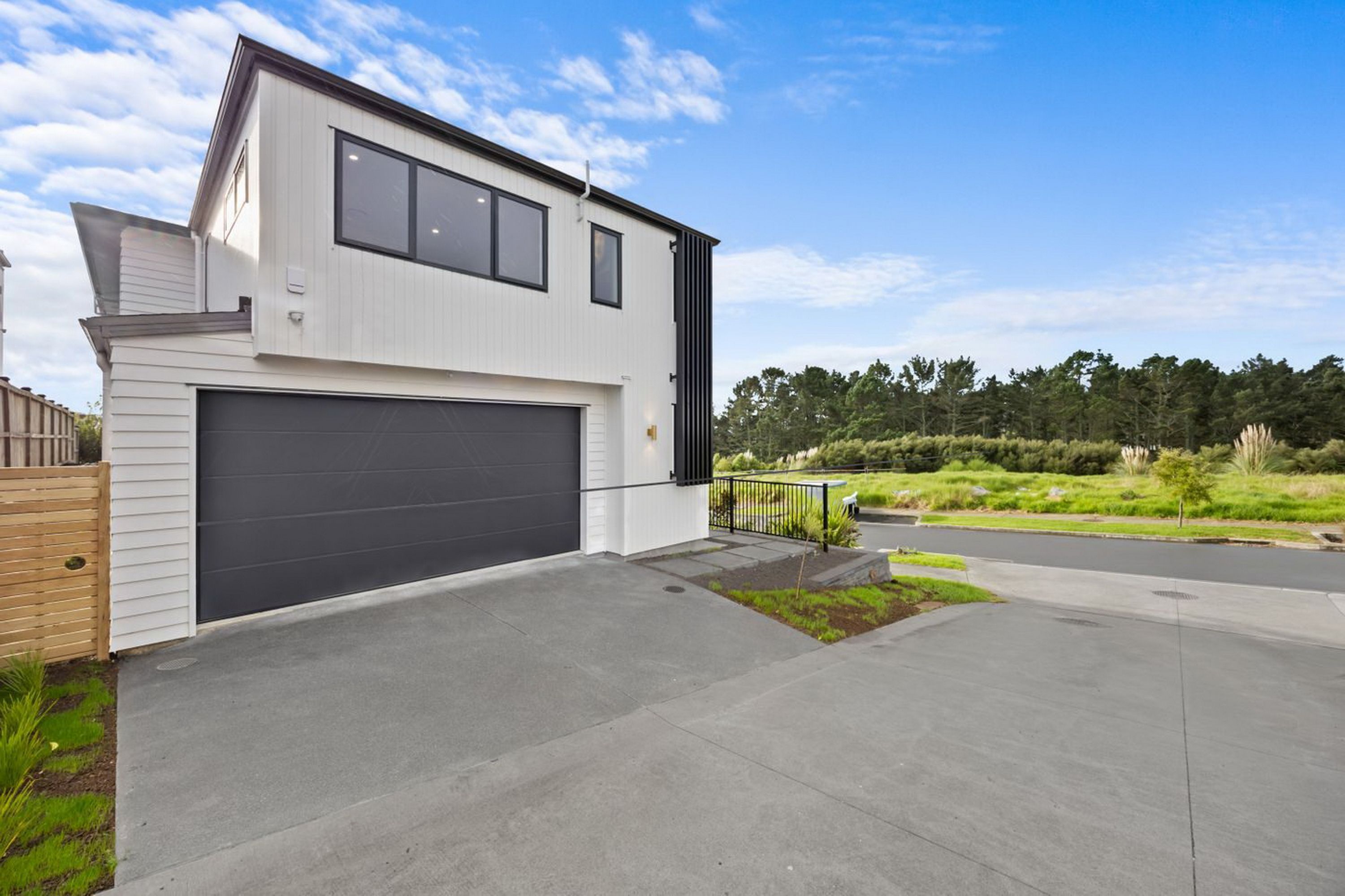 A modern two-story house with a garage, a well-maintained lawn, and a clear sky.