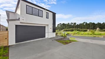A modern two-story house with a garage, a well-maintained lawn, and a clear sky.