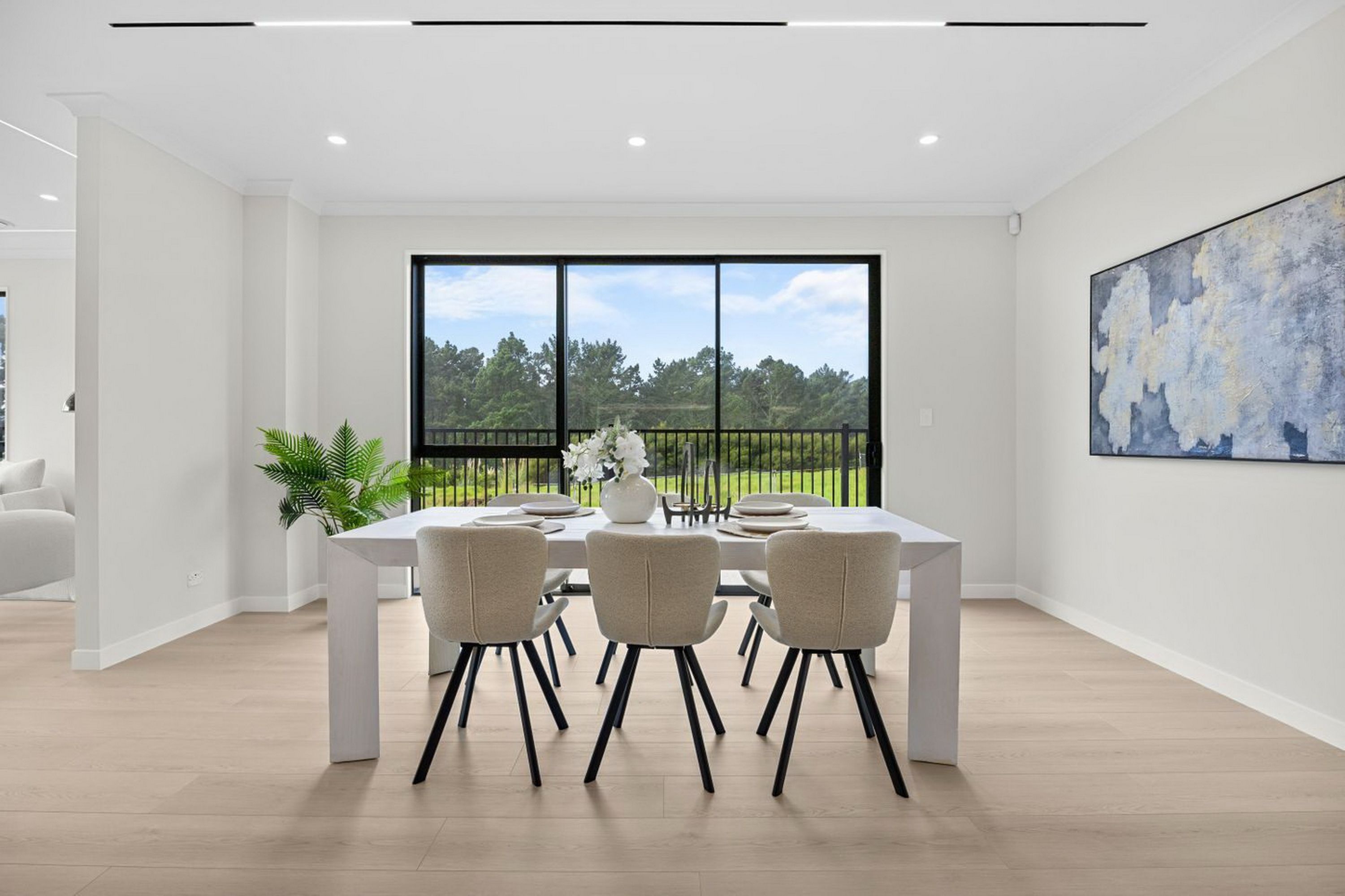 Un comedor moderno con un amplio ventanal, una mesa de comedor, sillas y una planta en maceta.