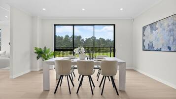 Un comedor moderno con un amplio ventanal, una mesa de comedor, sillas y una planta en maceta.