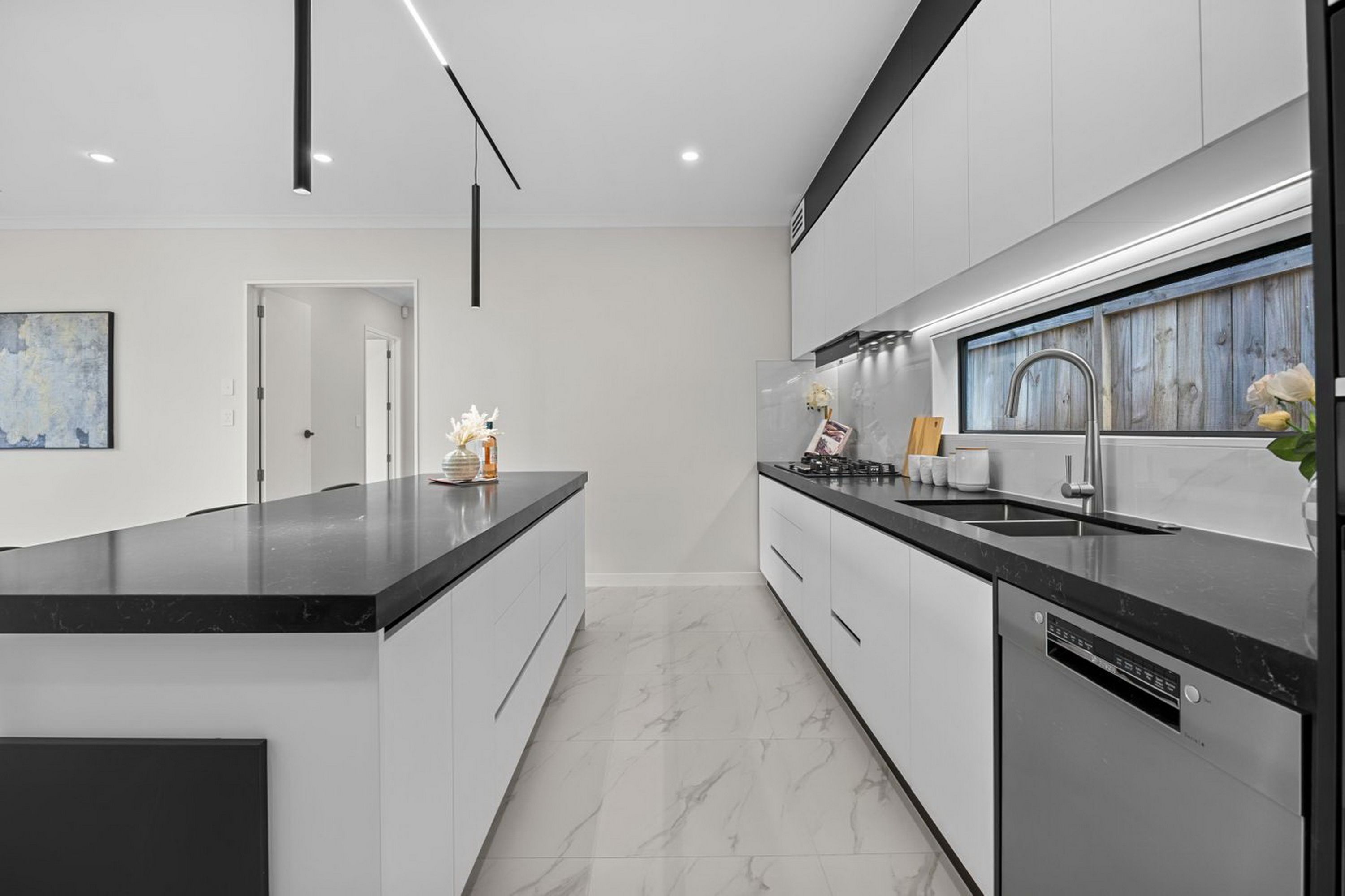 Une cuisine moderne dotée d’un îlot central, de meubles blancs et d’un lave-vaisselle encastré.